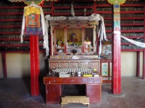 p1100150s An altar in the Narthang Monastery; the library of scripture printing tablets in the background.