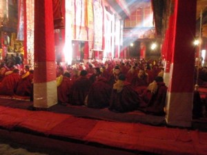 The sunlight streams through the butter-candle smoke and incense onto the chanting monks.